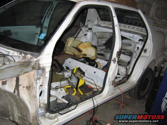 Interior of a dismantled white car, showing exposed frame and wiring