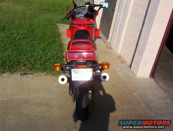 Rear view of a red motorcycle with dual exhaust pipes and a license plate