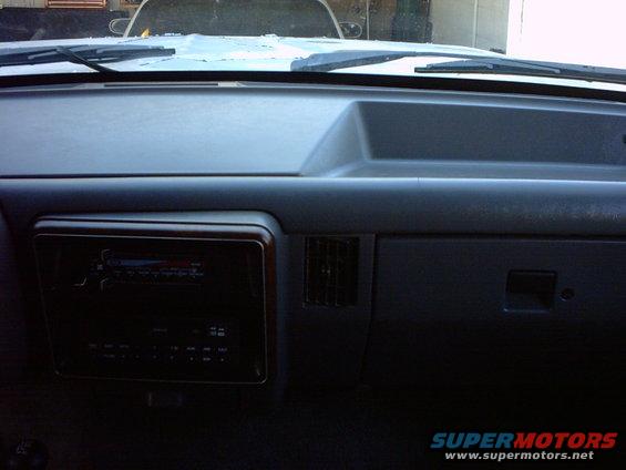 Dashboard of a 1990 Ford Bronco with wood-grain trim around the radio and a vent