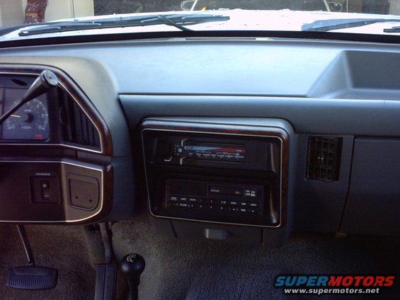Interior dashboard of a 1990 Ford Bronco with wood trim around the radio and gauges