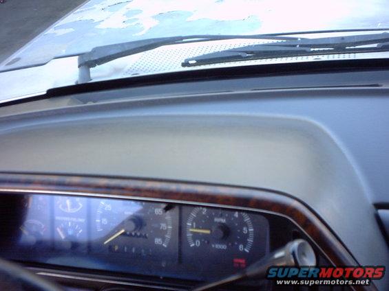 1990 Ford Bronco dashboard showing speedometer, tachometer, and windshield wipers. Wood trim accents the dash