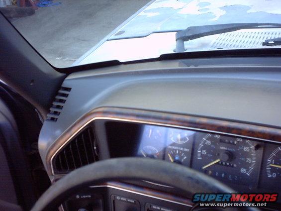 Dashboard view of an older truck, showing the steering wheel and instrument cluster with wood trim