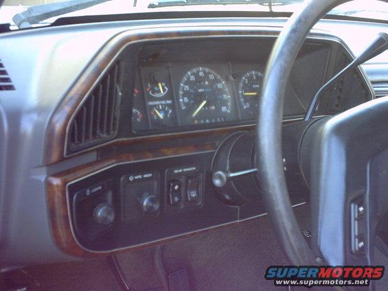 Dashboard interior with wood trim, gauges, and steering wheel. The speedometer reads 60 mph