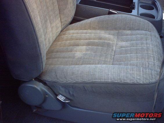 Close-up of a worn fabric car seat with a lever on the side