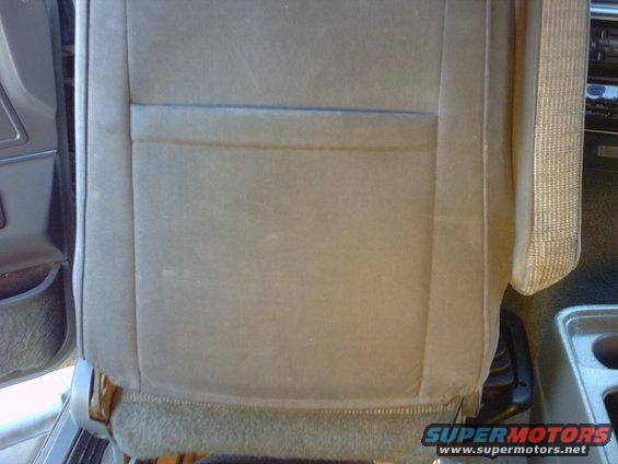 Close-up of a car's fabric seat with a pocket on the back. Seatbelt visible on the right