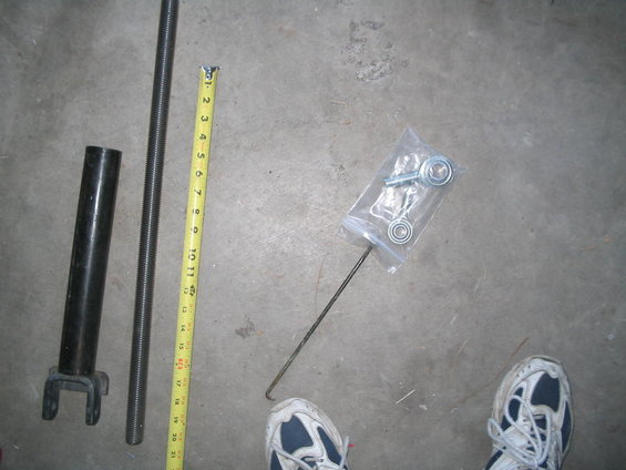 Measuring tape next to threaded rod, black pipe, and a bag of hardware