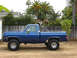 1979 Chevrolet C/K Pickup - Side view of a blue pickup truck with a roll bar and lifted suspension, parked outdoors.