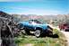 1979 Chevrolet C/K Pickup - A blue 1979 Chevrolet C/K Pickup navigates a rocky trail, with a red SUV visible in the background.
