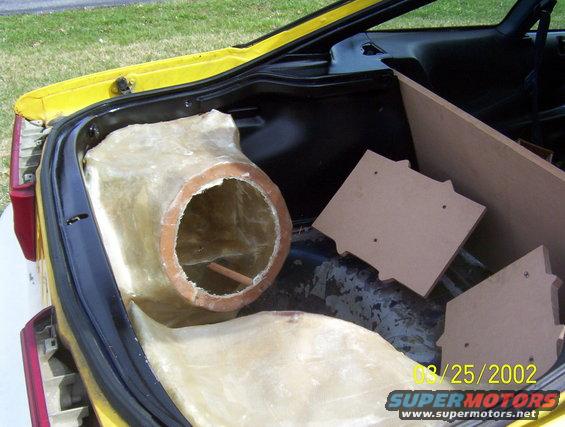 Yellow car trunk with custom fiberglass subwoofer enclosure and wood panels
