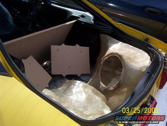 Yellow car trunk with custom fiberglass subwoofer enclosure and wooden mounting boards