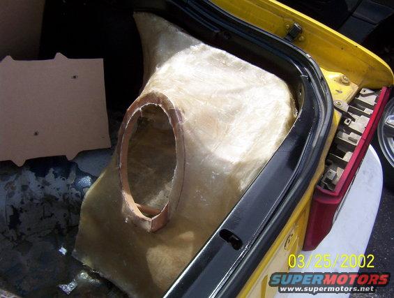 Fiberglass enclosure with speaker cutout in yellow car trunk, next to taillight