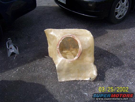 Fiberglass part with circular opening, next to a car jack and a black car