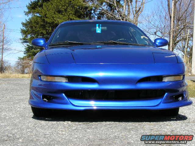 Front view of a blue 1994 Ford Probe parked on a gravel surface with trees in the background