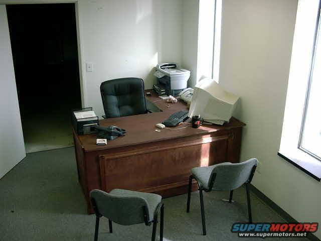 Office desk with computer, chairs, and telephone
