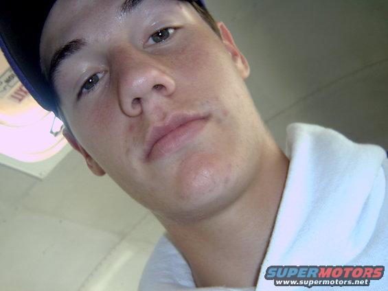 Close-up selfie of a young man wearing a blue baseball cap and a white hoodie