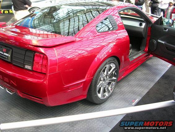 Red Saleen Mustang with door open, showing interior and chrome wheels. Saleen badging visible on rear