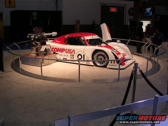 White and red race car with 'CompUSA' livery and exposed engine