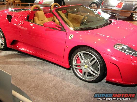 Pink Ferrari F430 Spider convertible with tan interior. Front wheel and fender visible
