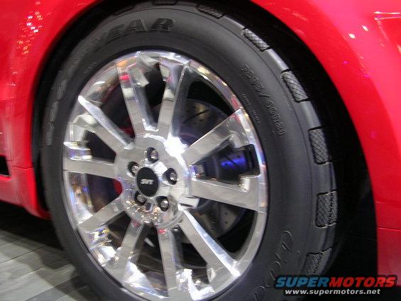 Red car wheel with silver multi-spoke rim and blue brake caliper