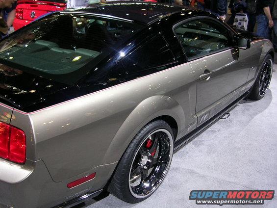 Gray coupe with black roof and chrome wheels, rear quarter view