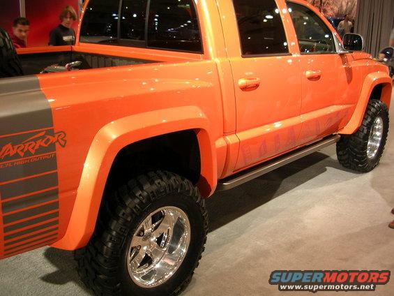 Orange pickup truck with 'Warrior' graphics on the rear fender and chrome wheels