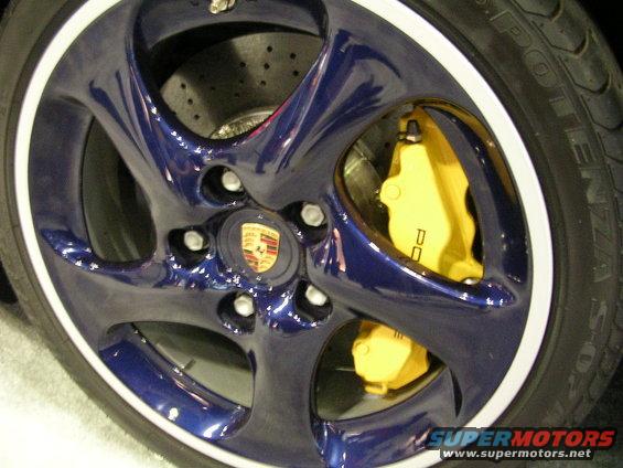 Blue wheel with yellow Porsche brake calipers and a Porsche badge