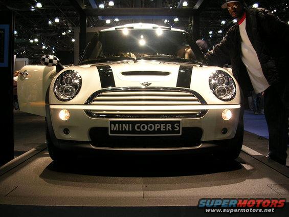 White Mini Cooper S with black stripes and a person standing next to it
