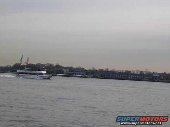 NY Waterway ferry boat moving on water with buildings and cranes in background