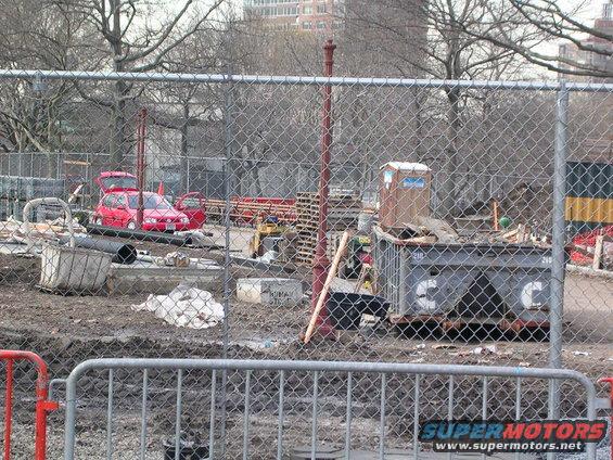 Red hatchback with doors and trunk open at a construction site