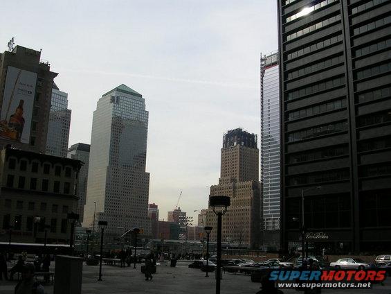 City street with tall buildings and parked cars under an overcast sky