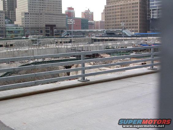 Construction site with concrete structures and metal railings, tall buildings in the background