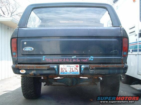 Rear view of a dark blue Ford Bronco with a bumper sticker that says "Why dont we d-do it in the road?"