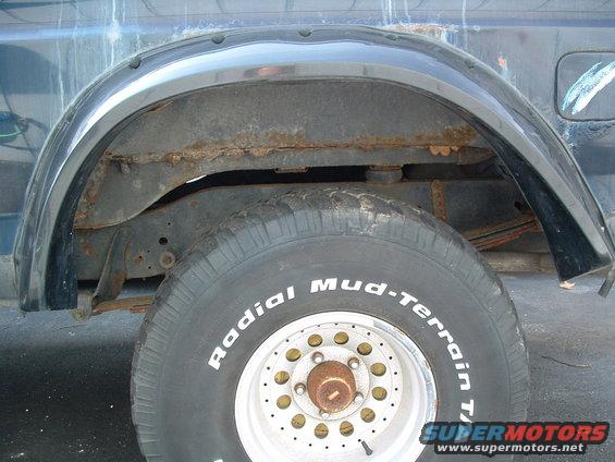 Dark blue SUV rear wheel well with rust on the frame and leaf springs, showing a BFGoodrich Radial Mud-Terrain T/A tire