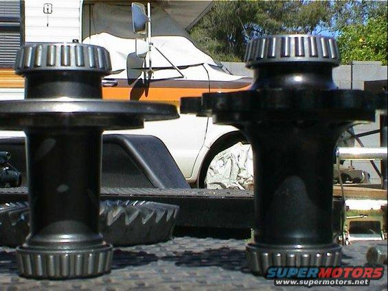 Two differential bearing and race sets in foreground. A covered vehicle with orange stripe and a trailer are in the background