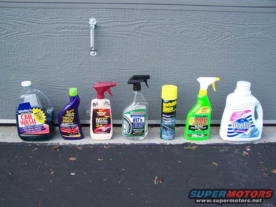 Several bottles of car cleaning products lined up in front of a garage door