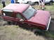 1985 Ford Bronco II - A red SUV is partially submerged in mud and grass, with several people observing the situation.