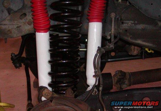 Close-up of front suspension with red-top shocks and black coil springs