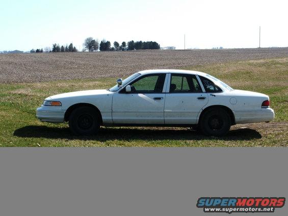 1996 Ford Crown Victoria police car, side view, parked in a field