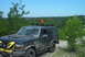 1993 Ford Bronco - Mud-covered 1993 Ford Bronco navigates an off-road trail with an orange flag on its roof rack.