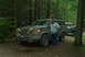 1993 Ford Bronco - A man stands next to a muddy 1992 Ford Bronco in a wooded area, with another vehicle visible behind it.