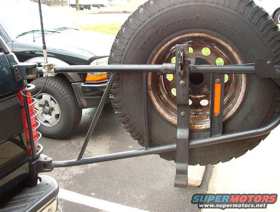 Spare tire carrier on dark SUV with another vehicle behind it