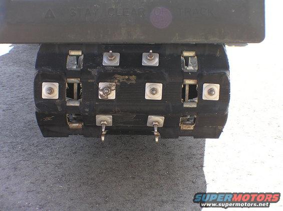 Close-up of a snowmobile track with metal studs and a warning label above