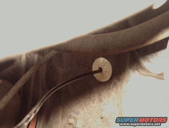 Hand throttle cable passing through firewall with white grommet
