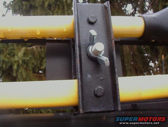 Roof rack mounting bracket with yellow bars and water droplets, close-up
