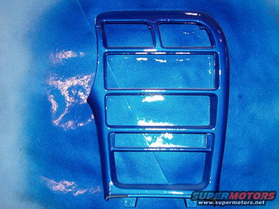 Blue metallic center console trim piece with multiple rectangular openings, showing paint chips