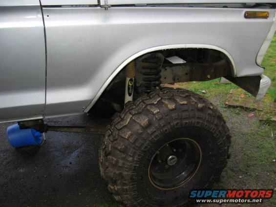 1976 Ford F-150 side view showing lifted suspension, large off-road tire, and blue bucket under driveshaft