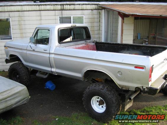 Silver pickup truck with lifted suspension and large tires, viewed from the side