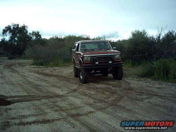 Red SUV with lifted suspension on a dirt road