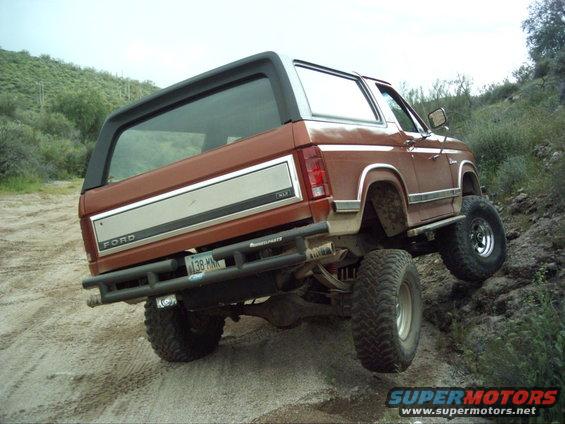 Brown Ford Bronco with lifted suspension and off-road tires climbing a dirt hill
