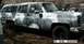 1979 Chevrolet Suburban - This Chevrolet Suburban, likely from the mid-1970s, is covered in a camouflage paint scheme and appears to be in a state of disrepair.